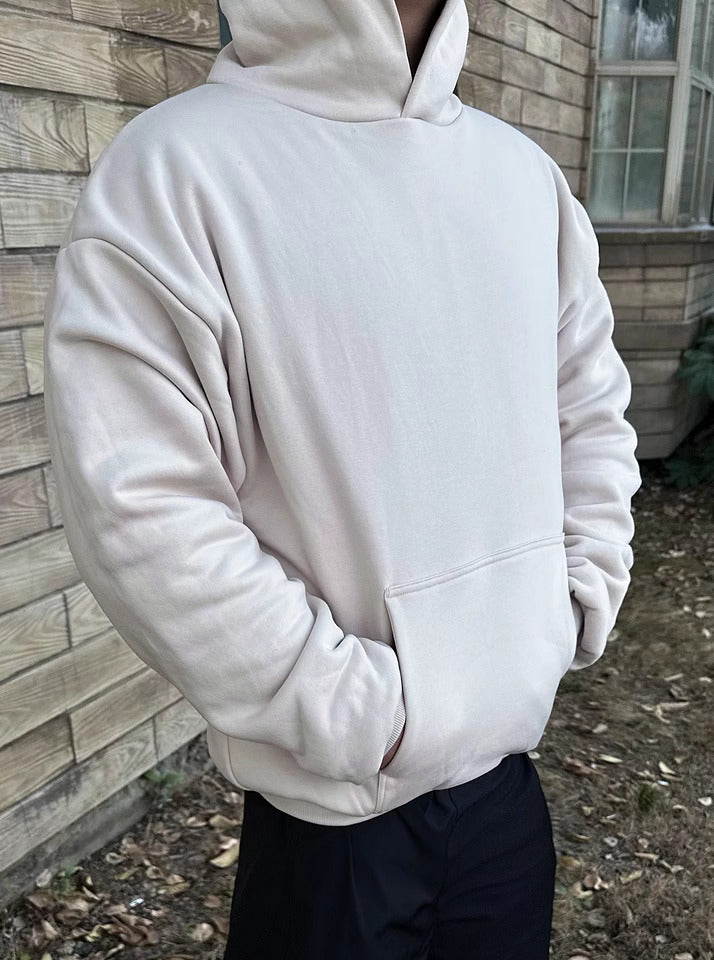Ein Model posiert in dem beigefarbenen 800 GSM Heavyweight Hoodie von Gradualbasics.